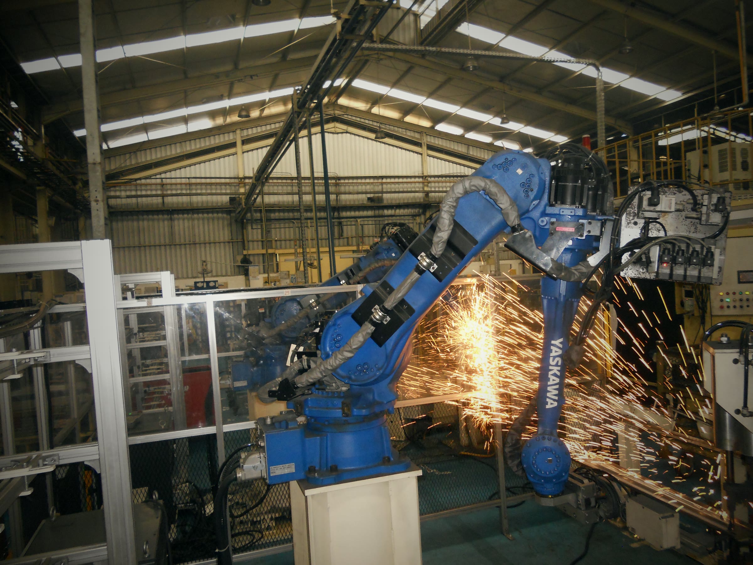 A welding robot throwing sparks on a factory floor